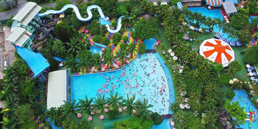 An aerial view of a water park with a big pool and numerous rides