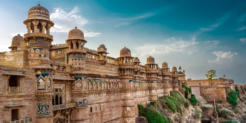 View of Gwalior Fort's massive stone walls and intricate architecture under a clear sky.