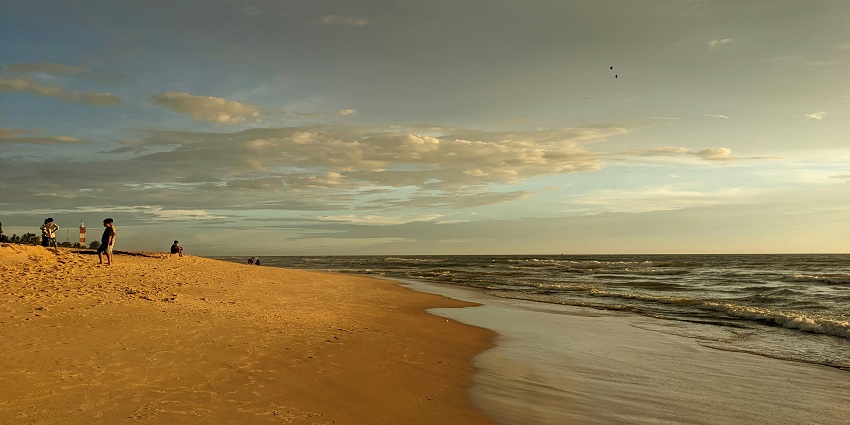 People enjoying Puri Beach with calm waves and clear sky, near Sudam Sand Art Museum