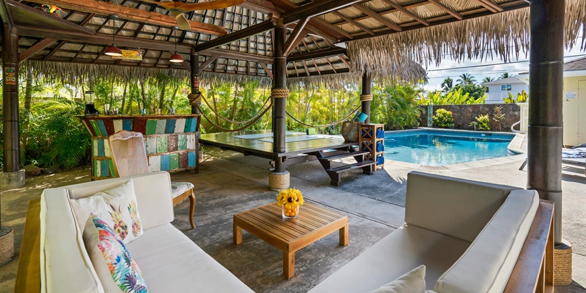 A cosy cabana beside a swimming pool, offering a relaxing retreat in a sunlit setting.