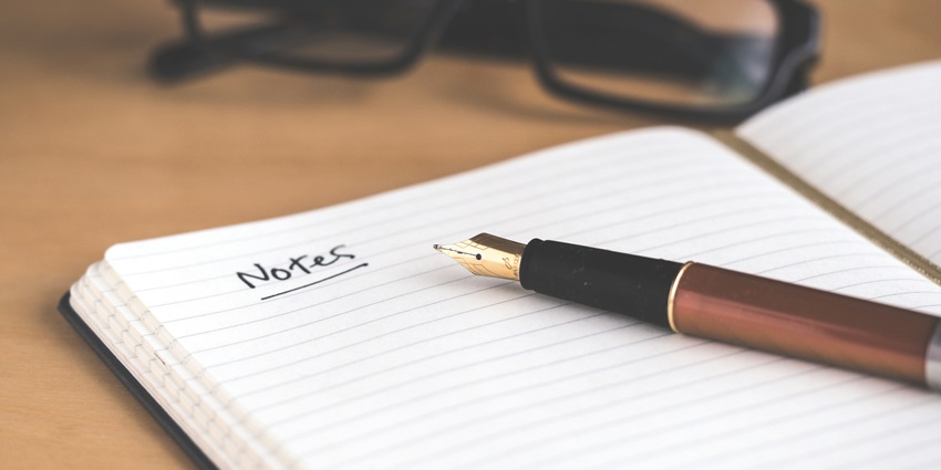 A close-up shot of a brown and black fountain pen kept on a white open notebook.