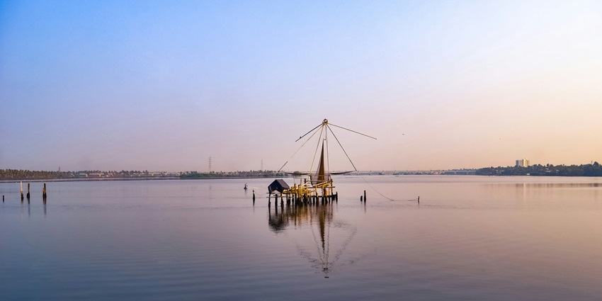 A serene body of water reflecting the sky, surrounded by lush greenery and distant hills
