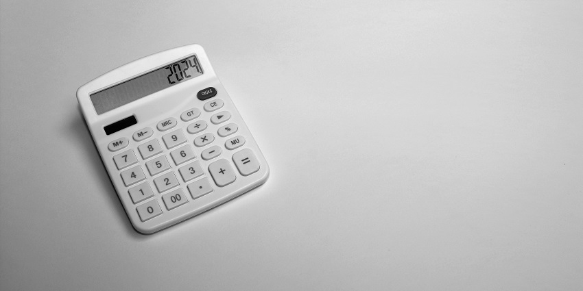 A selectively focused view of a white calculator with black numbers on it on a table.