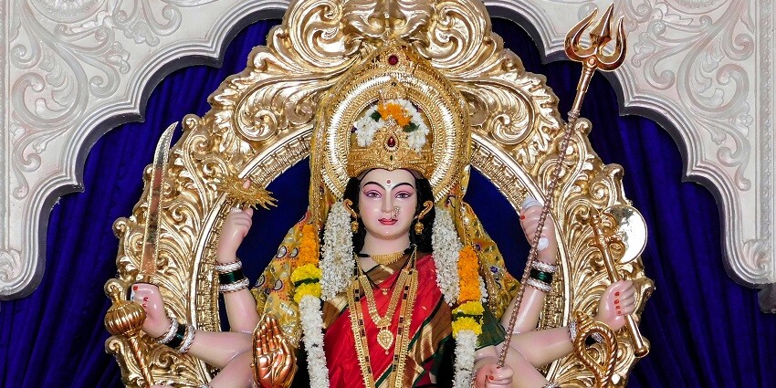 Gold and red Hindu deity figurine adorned with intricate details and vibrant colours