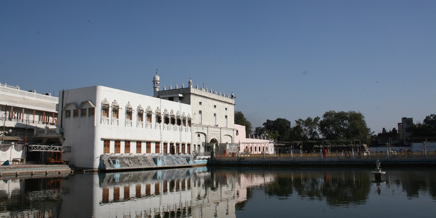 A wide angle shot of the Iconic Durgiana Temple and his scared pond taken under sunny sky