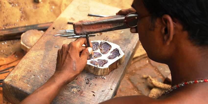 Artisan carving a wooden block for prints at the Anokhi Museum, celebrating textile heritage.