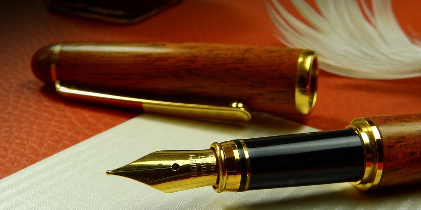 A close-up stunning view of a golden and brown fountain pen on a white notebook.