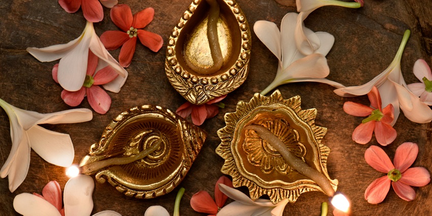 A lit diya beside vibrant flowers, creating a warm and festive atmosphere.