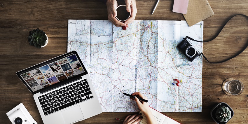 A person planning a trip while enjoying coffee at a cozy table with travel notes.