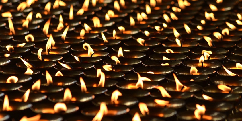 An image showing a closeup of a diyas in a temple features intricate architecture and carvings.