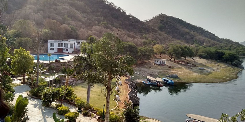 A scenic view of lush greenery and calm waters at Jaisamand Wildlife Sanctuary's lake