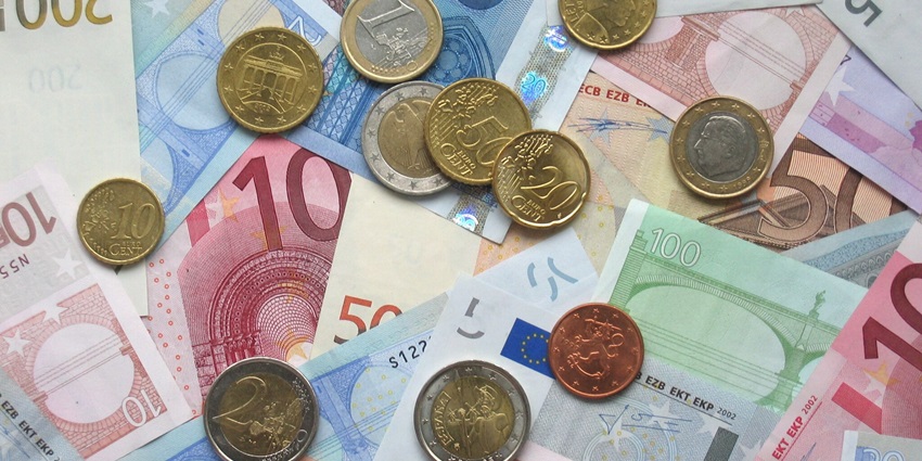 A bunch of cash and coins laid out on a table.