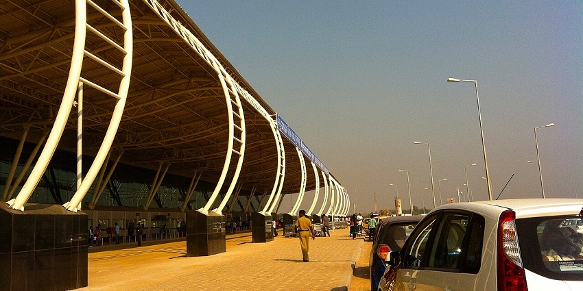 The outside of an airport during the evening, with cars standing in front.