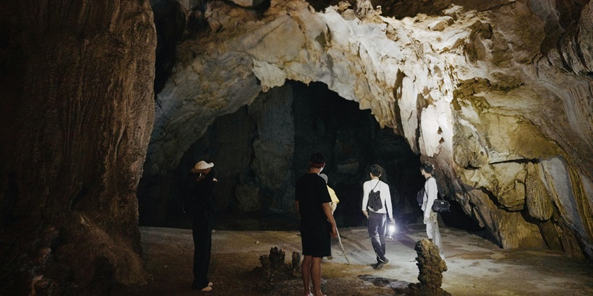A group of people navigating their path in the cave equipped with a lamp, bags, and a hatViewers of this file can see comments and suggestions