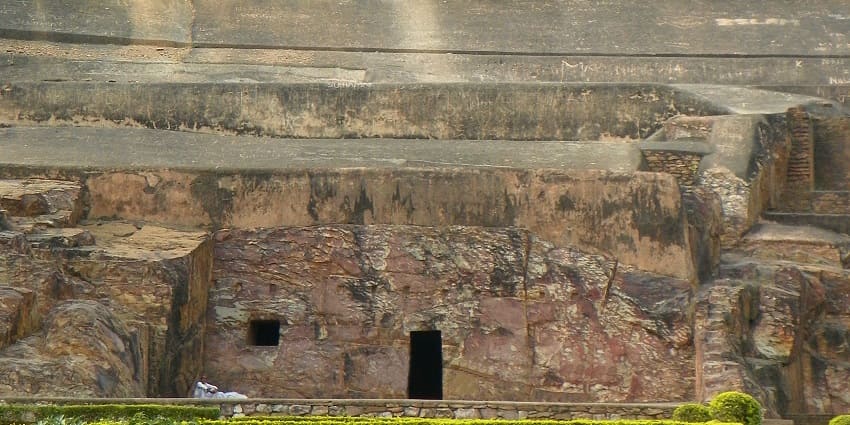 A scenic view of Sonbhandar Caves in Rajgir, with rock-cut structures surrounded by lush greenery