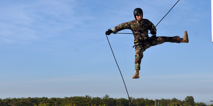 Image of a man bungee jumping with lush green surrounded view during day time
