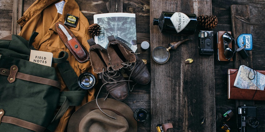 An image of all the travel things like shoes, a dairy, a bag, and a magnifying glass.