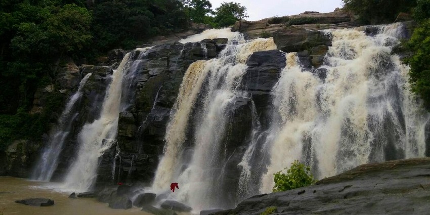 Picturesque view of the waterfalls, cascading down multiple tiers surrounded by lush green forest