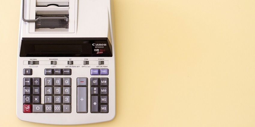 An aerial shot of a white calculator with different numbers on it sitting on a table.