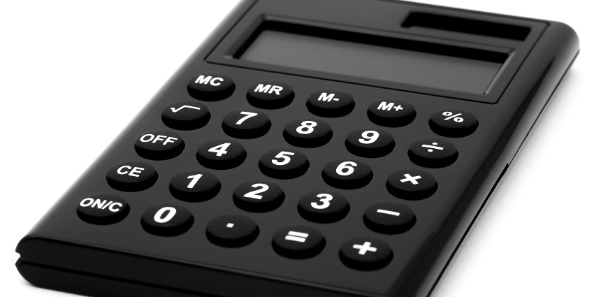 A selectively focused view of a black calculator on a plain white surface during the day.