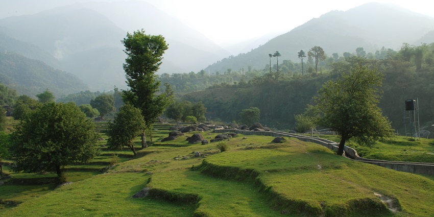 Picturesque view of Palampur in a misty weather surrounded by green mountains and field