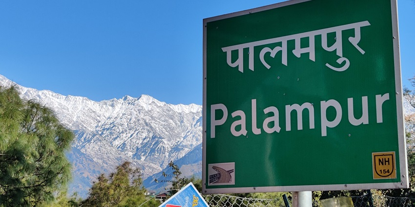 Image of Palampur signboard with backdrop snow covered mountains showing