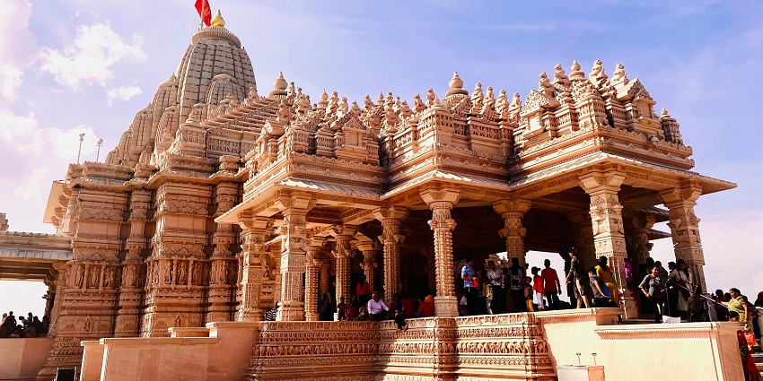 Ancient temple with detailed stone carvings and a majestic dome, surrounded by lush greenery and a clear blue sky