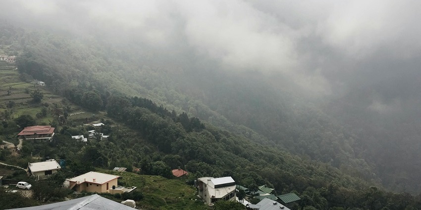 View of Pangot showcasing lush greenery and distant mountains under a clear sky.