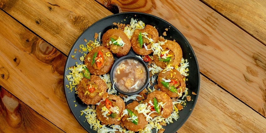 A tray of Pani Puri, with hollow puris filled with spiced water, potatoes, and chickpeas.