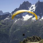 A person indulged in a thrilling adventure on a yellow parachute enjoying scenic views.