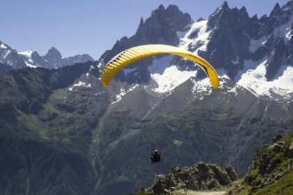 A person indulged in a thrilling adventure on a yellow parachute enjoying scenic views.