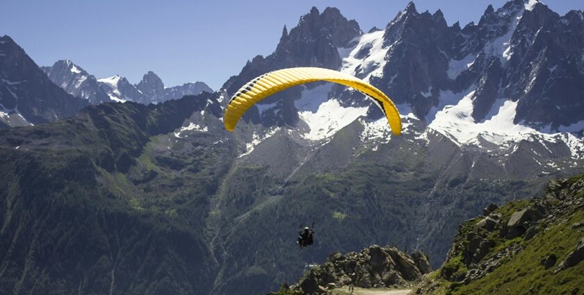 A person indulged in a thrilling adventure on a yellow parachute enjoying scenic views.