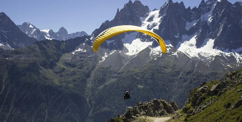 A man in a yellow parachute enjoying the mesmerising natural beauty from the above.