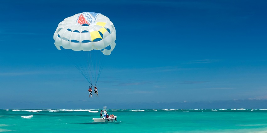 A breathtaking view of people enjoying parasailing surrounded by azure waters in the day.