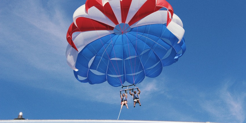Two tourists landing after parasailing at the Palolem beach with the clear blue sky at the backdrop