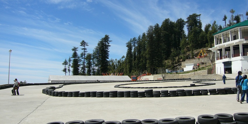 Amusement rides at Kufri Fun World set on a green hillside with mountains in view