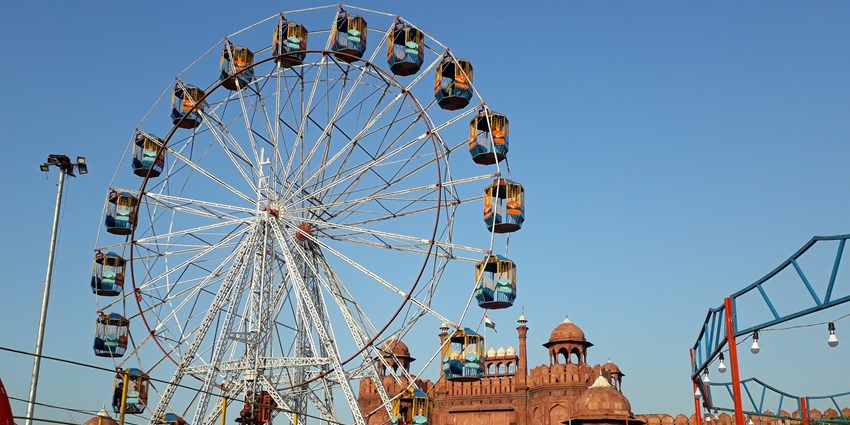 View of the mela, large ferris wheel, eateries and local stalls surrounded by visitors