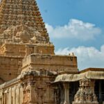 A breathtaking view of a temple with brown architecture with a group of people in front.