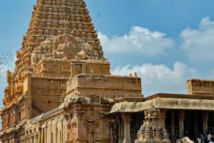 A breathtaking view of a temple with brown architecture with a group of people in front.