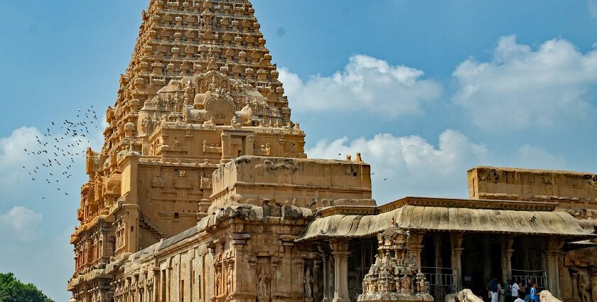 A breathtaking view of a temple with brown architecture with a group of people in front.