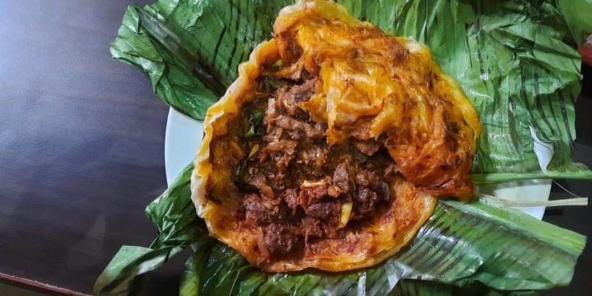 Parotta and Beef Fry, a delish cuisine served on a plate while being garnished with onion.