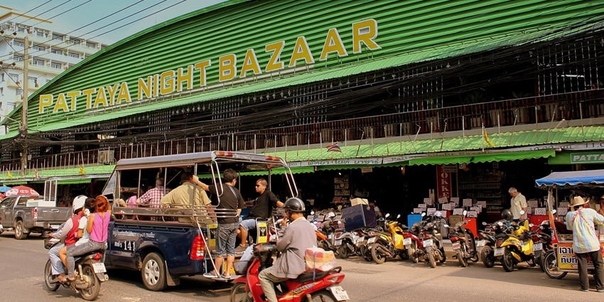 Entrance of Pattaya Night Bazaar for buying things in Thailand with an auto passing by.