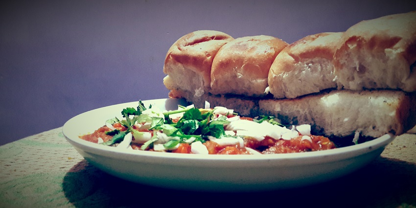 A view of a plate of tasty Pav Bhaji with a slice of buttered pav and sprinkling, the best street food in Surat.