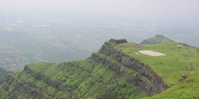 Picturesque view of the Pavagadh hills surrounded by lush greenery under clear blue sky