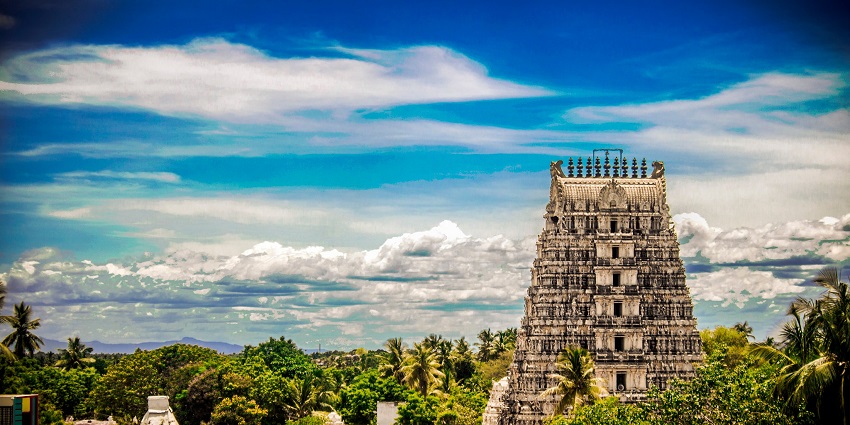 A picture of a temple taken from a distance with its 100-ft Gopuram visible under a clear sky