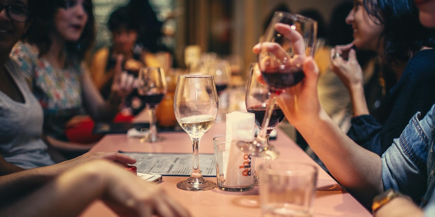People enjoying drinks and chatting around a dining table, with glasses - Nightlife In Vizag