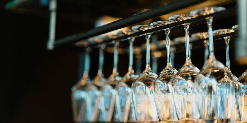 Image of glasses in row hanging upside down for decorations and dim lights in the background