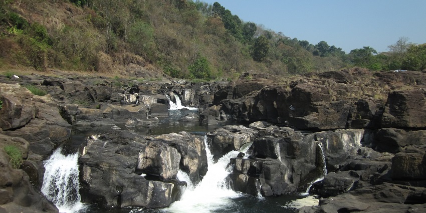 A stunning waterfall cascading over rocks surrounded by lush greenery in Perunthenaruvi, Pathanamthitta.