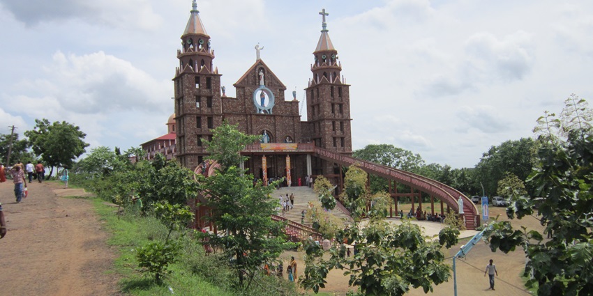 Church on Nirmala Giri hill with white steeple surrounded by green trees and sky