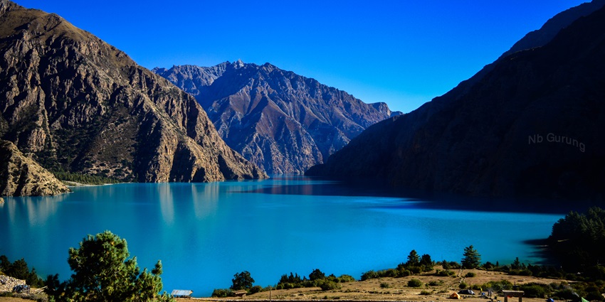 Phoksundo Lake is surrounded by snow-capped mountains and lush forests.